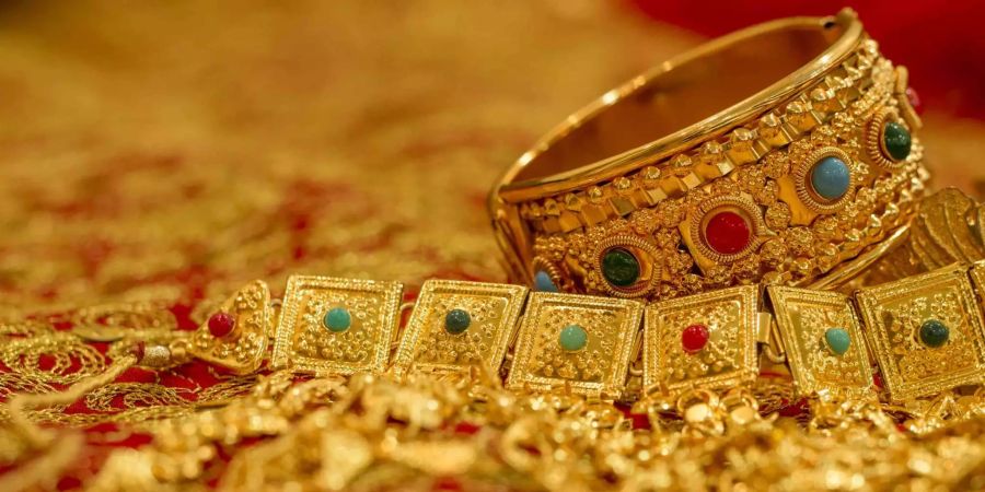 Bahrainischer Goldschmuck liegt auf einem goldbesticktem roten Tuch.