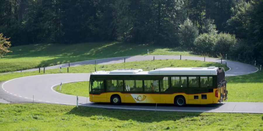 Ein Postauto fährt auf einer Landstrasse.