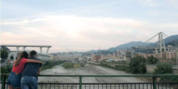 Ein Paar steht auf einer Brücke, von der man auf die Überreste des Polcevera-Viadukts in Genua sehen kann. Ein Paar steht auf einer Brücke, von der man auf die Überreste des Polcevera-Viadukts in Genua sehen kann.