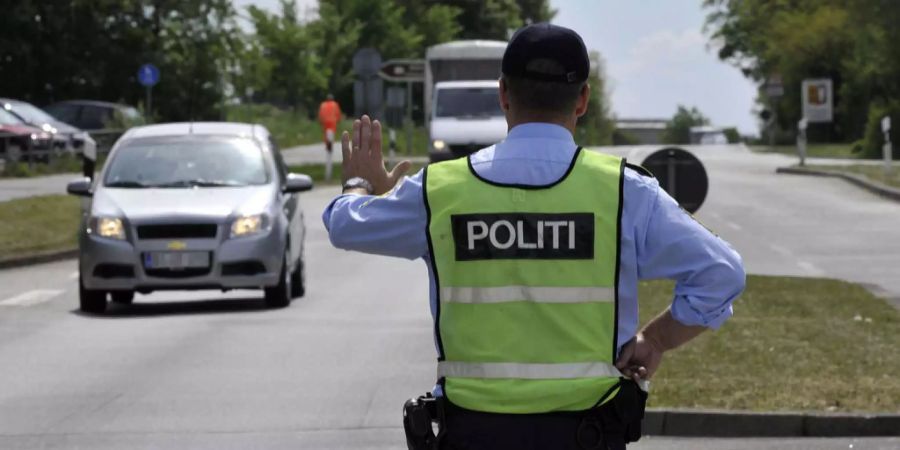 Ein Beamter der dänischen Polizei stoppt am deutsch-dänischen Grenzübergang Pattburg einen PKW.