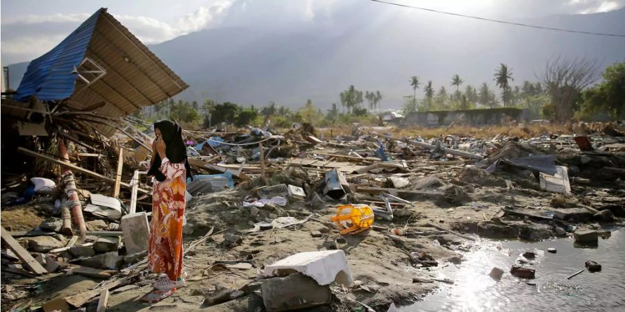 Eine Frau läuft über die Trümmer nach dem Erdbeben in Indonesien.