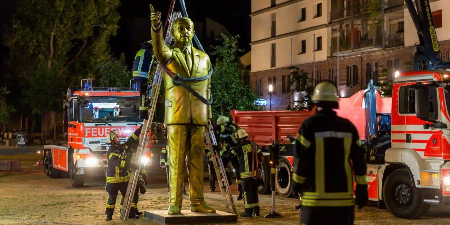 Feuerwehrleute heben in Wiesbaden (D) eine Statue des türkischen Staatspräsidenten Recep Tayyip Erdogan mit Hilfe eines Krans von einem Platz.