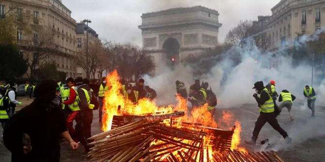 Demonstranten laufen an einer brennenden Barrikade in der Nähe des Arc de Triomphe (Triumphbogen) während einer Demonstration vorbei.