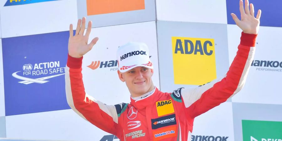 Der deutsche Rennfahrer Mick Schumacher winkt bei einer Siegerehrung.