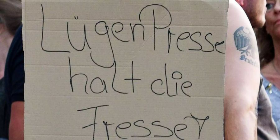 Ein Teilnehmer einer Kundgebung rechter Gruppen hält ein Plakat mit der Aufschrift «LügenPresse halt die Fresse!» in die Luft.