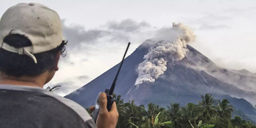 Ein freiwilliger Helfer benutzt sein Walkie-Talkie, während er den Vulkan Mount Merapi während einer Eruption überwacht. Der Vulkan Merapi ist erneut ausgebrochen und spukte mehrere Stunden glühende Asche und Gestein. Foto: Slamet Riyadi/AP/dpa