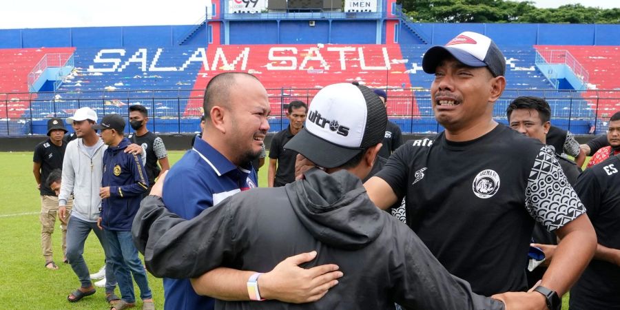 Fans und Offizielle des Arema FC umarmen sich nach einem Gebet im Kanjuruhan-Stadion, wo es zu einer Massenpanik kam.