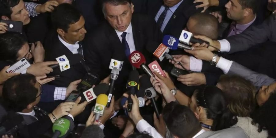 Brasiliens Präsident Jair Bolsonaro (M) spricht mit Journalisten, nachdem er das Dekret zum gelockerten Waffenrecht unterzeichnet hat. Foto: Eraldo Peres/AP