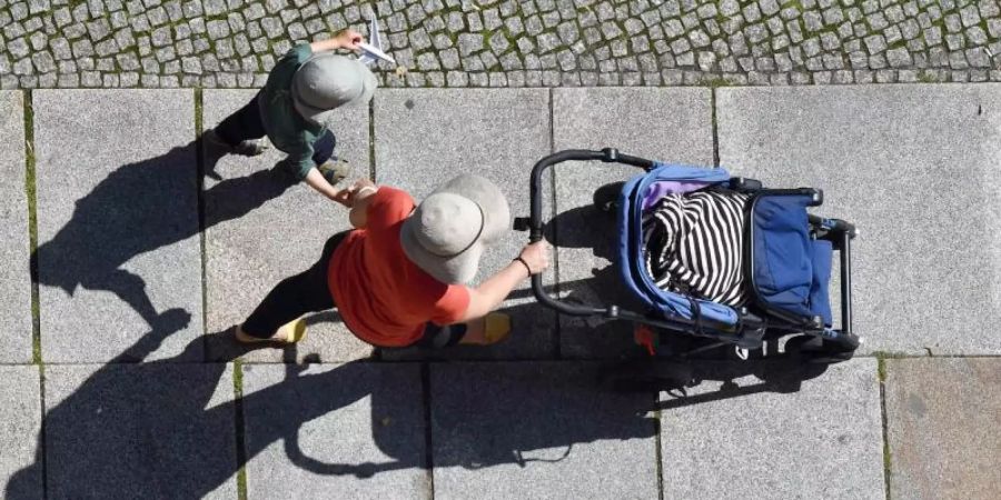 Eine Frau und ein Kind auf einem Gehweg. Der BGH hat zum Thema verbotene Leihmutterschaft geurteilt. Foto: Jens Kalaene/Symbol