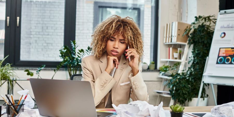 Frau sitzt am Laptop und telefoniert