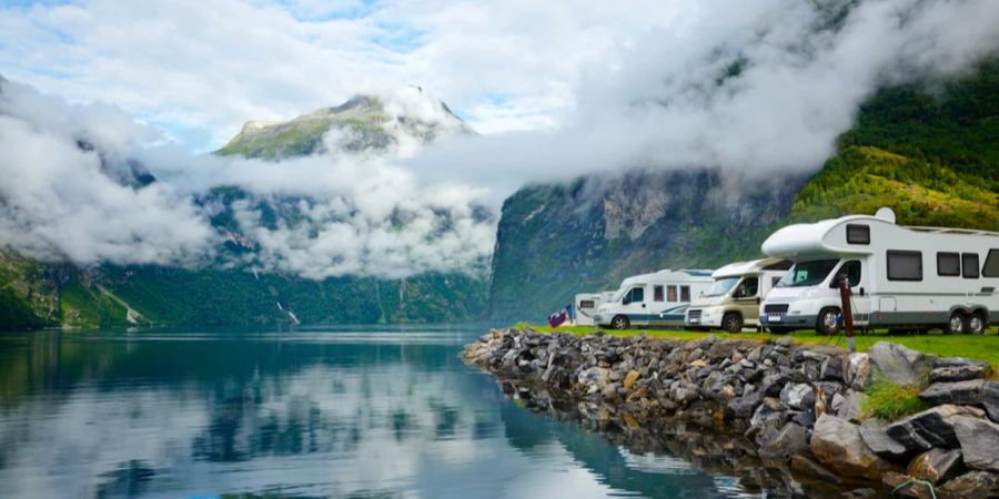 Camper stehen in einer Reihe an einem Bergsee