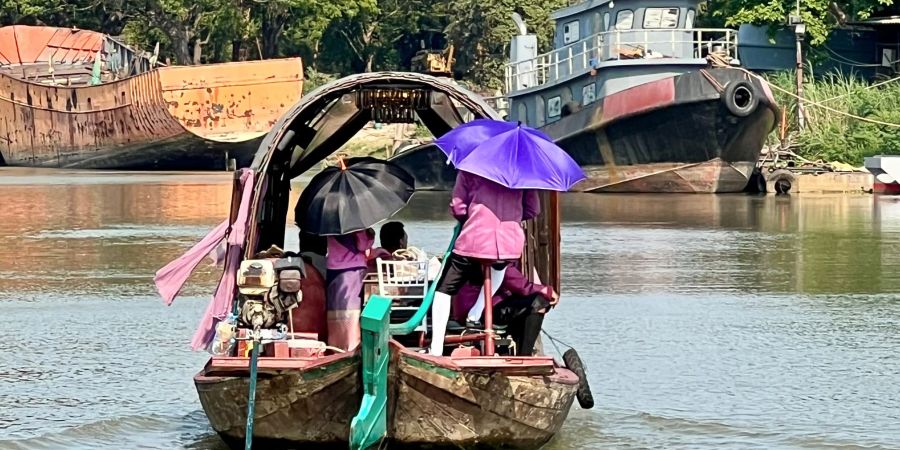 Menschen auf dem Pa Sak River schützen sich mit Sonnenschirmen vor der Sonneneinstrahlung und der extremen Hitze in Thailand.