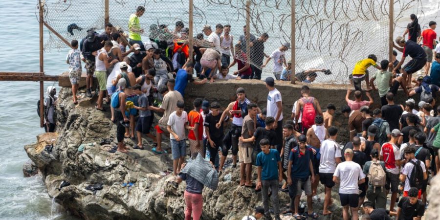 Menschen durchbrechen den Stacheldrahtzaun, als sie versuchen, von der nordmarokkanischen Stadt Fnideq in die spanische Exklave Ceuta zu gelangen. Foto: STR/AP/dpa