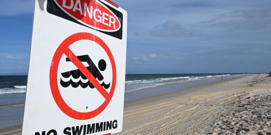 ARCHIV - Ein Schild mit der Aufschrift «Gefahr - Schwimmen verboten» steht an dem Strand Woorim Beach auf Bribie Island. Foto: Darren England/AAP/dpa