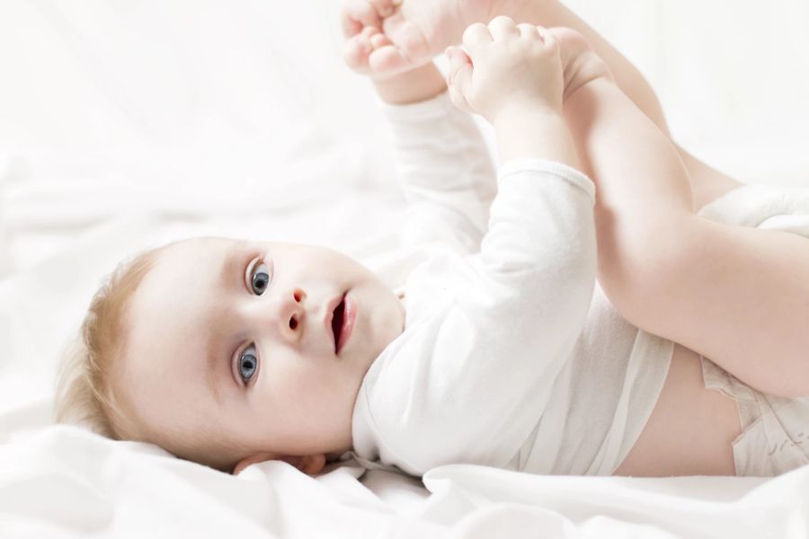 baby hält füßchen fest