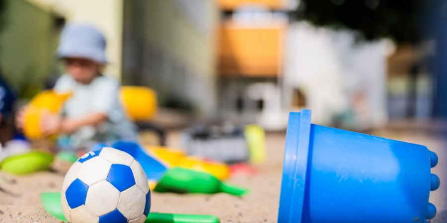 Ein Kind spielt in einem Sandkasten - wo haben dessen Eltern wohl Eimerchen, Schaufeln und den kleinen Ball gekauft, im Internet oder im Geschäft?