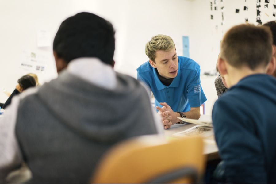 Ein Zivildienstleistender hilft Schülern bei ihren Aufgaben in einer Schule in Kehrsatz BE, im Dezember 2016.