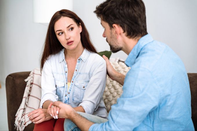 Offene Gespräche helfen nur, wenn sie konstruktiv bleiben und nicht belasten. Mann spricht mit Frau auf Sofa