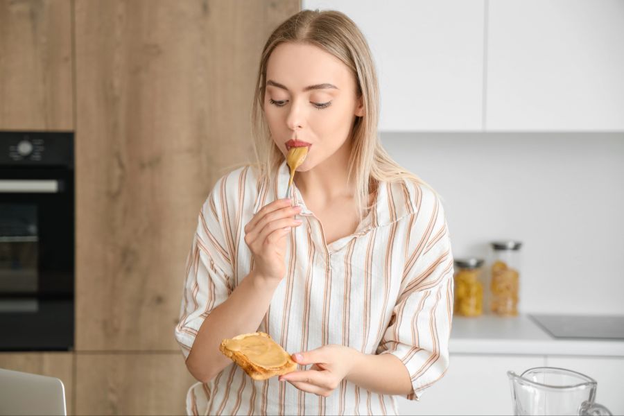 Frau mit Löffel, Erdnussbutter und Toast