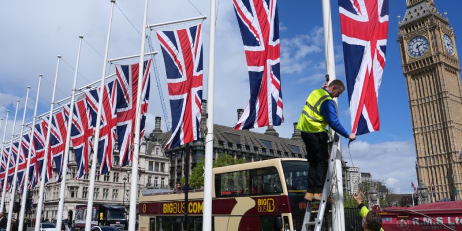 Arbeiter hissen britische Fahnen auf dem Parliament Square. Foto: Kin Cheung/AP/dpa