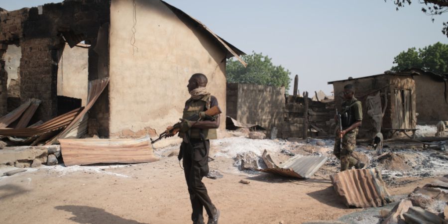 ARCHIV - Soldaten patrouillieren vor niedergebrannten Häusern, Tage nach einem Angriff in dem Dorf Woro. Bewaffnete haben bei einem Angriff in Nigeria Dutzende Menschen getötet. Foto:...