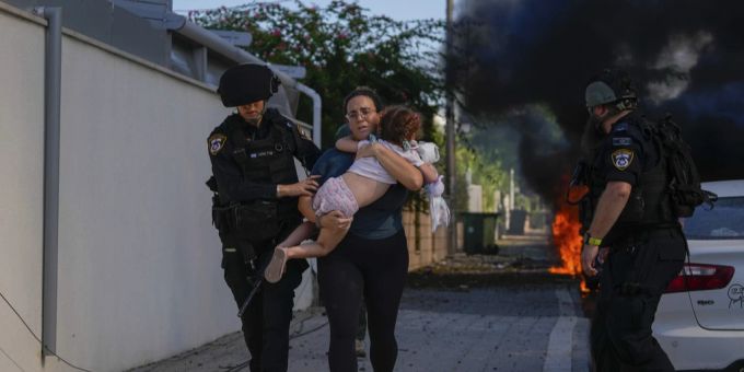 Israelische Polizeibeamte evakuieren 2023 eine Frau und ein Kind von einem Ort, der von einer aus dem Gazastreifen abgefeuerten Rakete getroffen wurde. Israelische Polizeibeamte