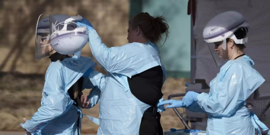 Im Kampf gegen die Lungenkrankheit: Gesundheitsmitarbeiter ziehen ihre Schutzkleidung an, bevor Menschen auf das neue Coronavirus getestet werden. Foto: Philip B. Poston/The Aurora Sentinel/AP/dpa