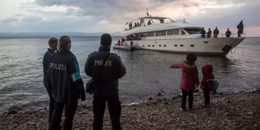 Sicherheitspersonal der Frontex sieht zu, wie Migranten aus einer Yacht an der griechischen Insel Lesbos steigen.