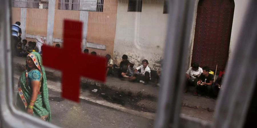 Menschen auf der Strasse Indiens sind durch einen Krankenwagen zu sehen.