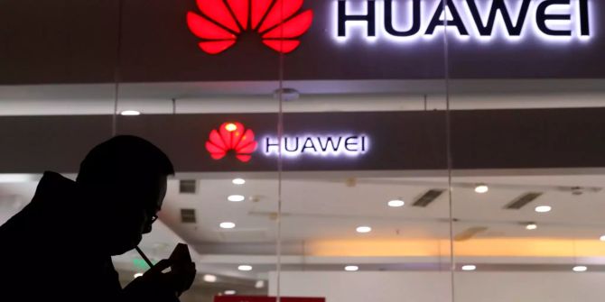 Ein Mann zündet eine Zigarette vor einem Huawei-Store an.