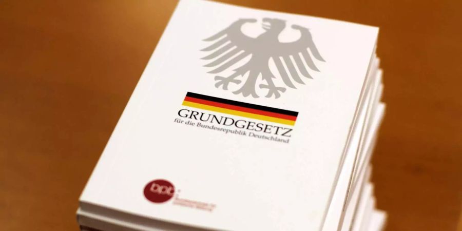 Mehrere Ausgaben des Deutschen Grundgesetzes liegen gestapelt.