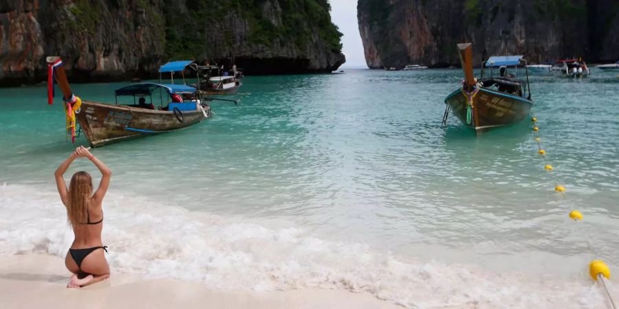 Eine Frau sitzt am Strand der Maya Bay, dem Strand, der durch den Film «The Beach» bekannt wurde.