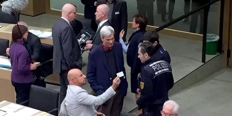 Stefan Räpple (sitzend, l), Abgeordneter der AfD im Landtag von Baden-Württemberg, spricht während einer Plenarsitzung mit Polizisten.