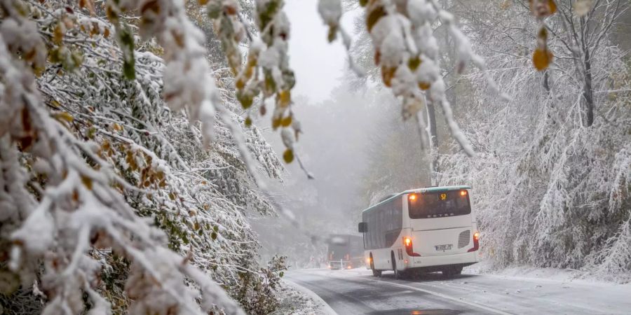 Ein Bus und ein LKW fahren durch den ersten Schnee.