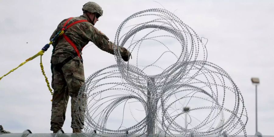 Ein Soldat der USA befestigt die Grenze zu Mexiko mit Stacheldraht.