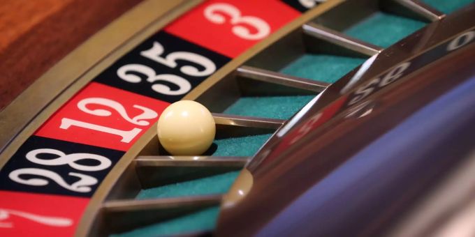 Beim Russisch Roulette wird kein Ball über eine Spielbank gerollt, sondern die Munitionstrommel eines Revolvers mit einer Kugel darin gedreht. Eine Kugel liegt in einer Spielbank im Kessel eines Roulette-Tisches.