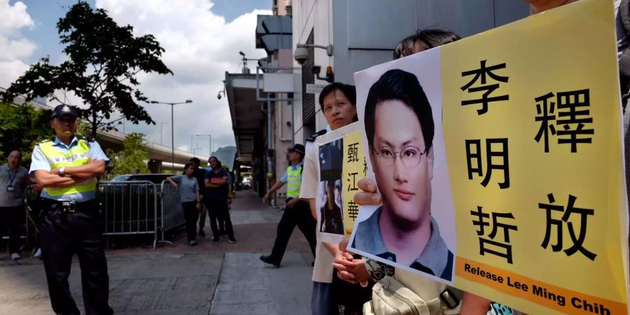 Menschen demonstrieren in Hongkong (China) mit Fotos des taiwanesischen Menschenrechtsaktivisten Lee Ming-che.