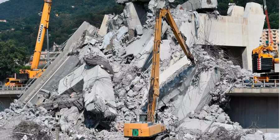 Bagger entfernen Trümmer der teilweise eingestürzten Morandi Autobahnbrücke, um die letzten Vermissten zu finden in Genua (IT).