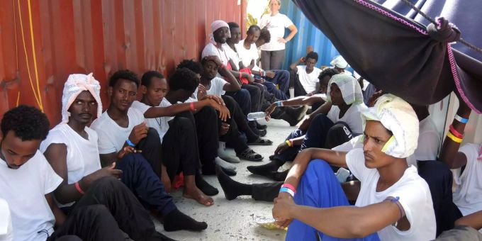 Migranten sitzen geschützt vor der Sonne unter Planen. Migranten sitzen geschützt vor der Sonne unter Planen.