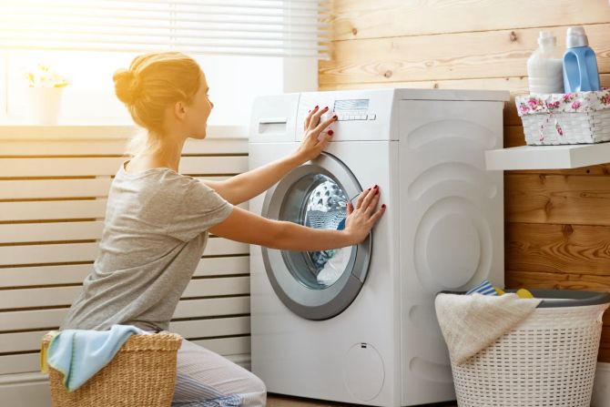 Frau schaltet Waschmaschine an