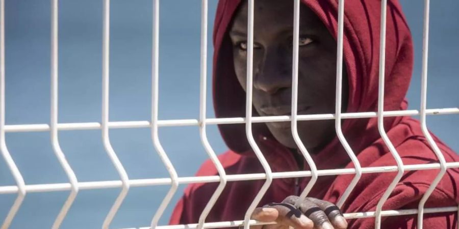 Ein Flüchtling steht an einem Zaun im Hafen von Algeciras. Die Innen- und Aussenminister der EU-Staaten über eine gemeinsame Linie in den Beziehungen zu Transit- und Herkunftsstaaten von Migranten beraten. Foto: Marcos Moreno/AP/dpa