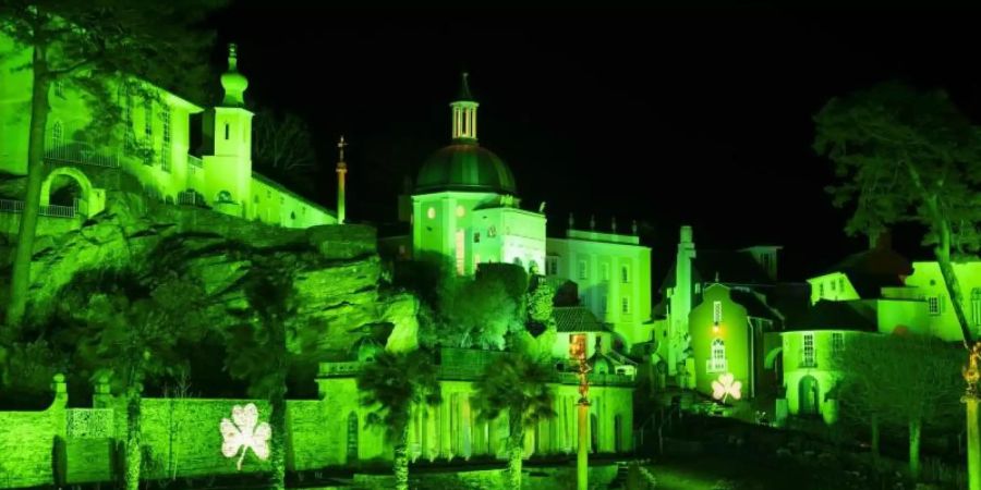 Das Dorf Portmeirion in Nordwales wird anlässlich des St. Patrick's Days grün beleuchtet. An mehreren Fassaden ist ein Kleeblatt abgebildet. Foto: Jon Super/PA Wire/dpa