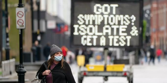 21.05.2021, Grossbritannien, Bolton: Eine Frau geht in Bolton, Grossbritannien, an einem öffentlichen Informationsschild vorbei. Coronavirus - Grossbritannien