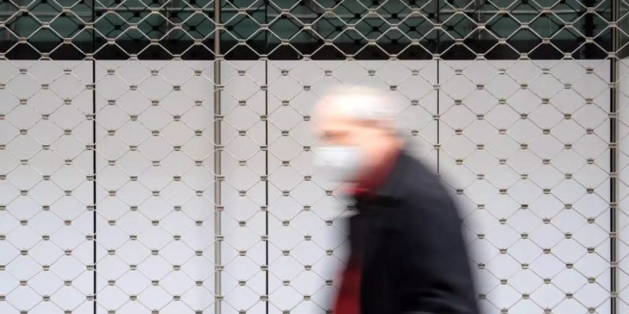 Ein Mann geht in einer Innenstadt an einem geschlossenen Geschäft vorbei. Foto: Sven Hoppe/dpa
