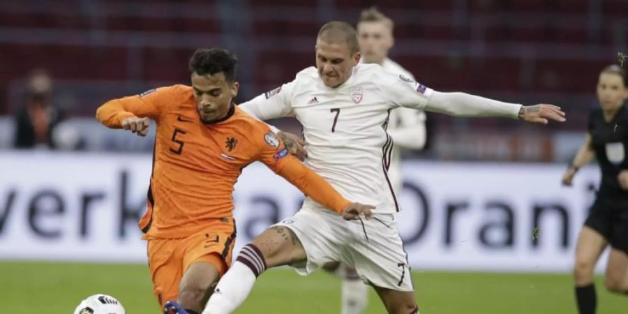 Der Lette Antonijs Cernomiordijs (r) und der Niederländer Owen Wijndal kämpfen um den Ball. Foto: Peter Dejong/AP/dpa