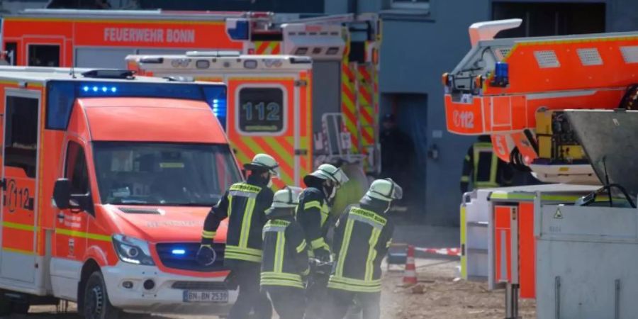 Feuerwehrleute tragen ihre Ausrüstung zur Einsatzstelle auf die Baustelle in Bonn. Foto: Henning Kaiser/dpa