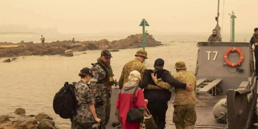 In der Küstenstadt Mallacoota bringt die Marine Menschen in Sicherheit, die sich an den Strand gerettet hatten. Foto: Pois Helen Frank/Royal Australian Navy/AP/dpa