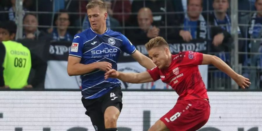 Bielefelds Joakim Nilsson (l) im Kampf um den Ball mit Santiago Ascacibar (r) vom VfB Stuttgart. Foto: Friso Gentsch