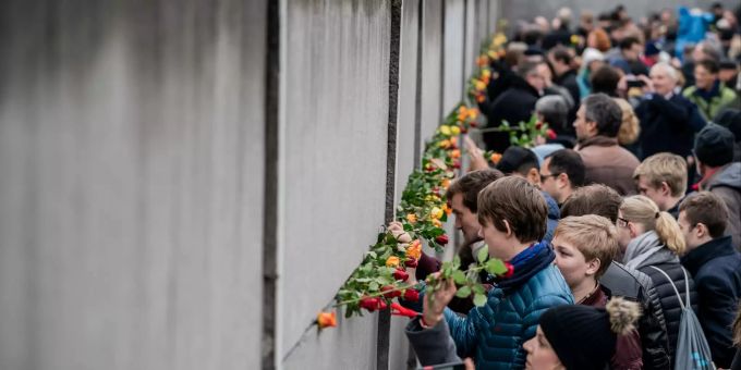 Besucher stecken Blumen bei der Gedenkveranstaltung der Stiftung Berliner Mauer an der Bernauer Strasse in Mauerschlitze der Hinterlandmauer. Bundespräsident Steinmeier und Bundeskanzlerin Merkel erinnern bei der Gedenkveranstaltung gemeinsam mit den Staatsoberhäuptern Polens, der Slowakei, Tschechiens und Ungarns an die Öffnung der Berliner Mauer vor 30 Jahren. 30. Jahrestag Mauerfall