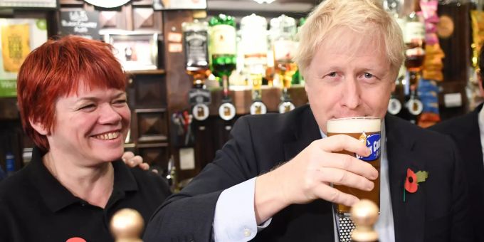 Boris Johnson (r), Premierminister von Grossbritannien, steht hinter der Bartheke der Lych Gate Tavern und trinkt ein Bier während er sich mit Militärveteranen trifft. Brexit